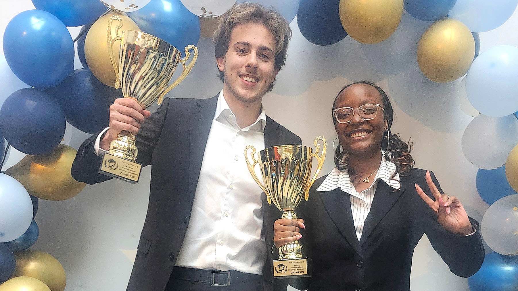Two U of GH students hold gold trophies