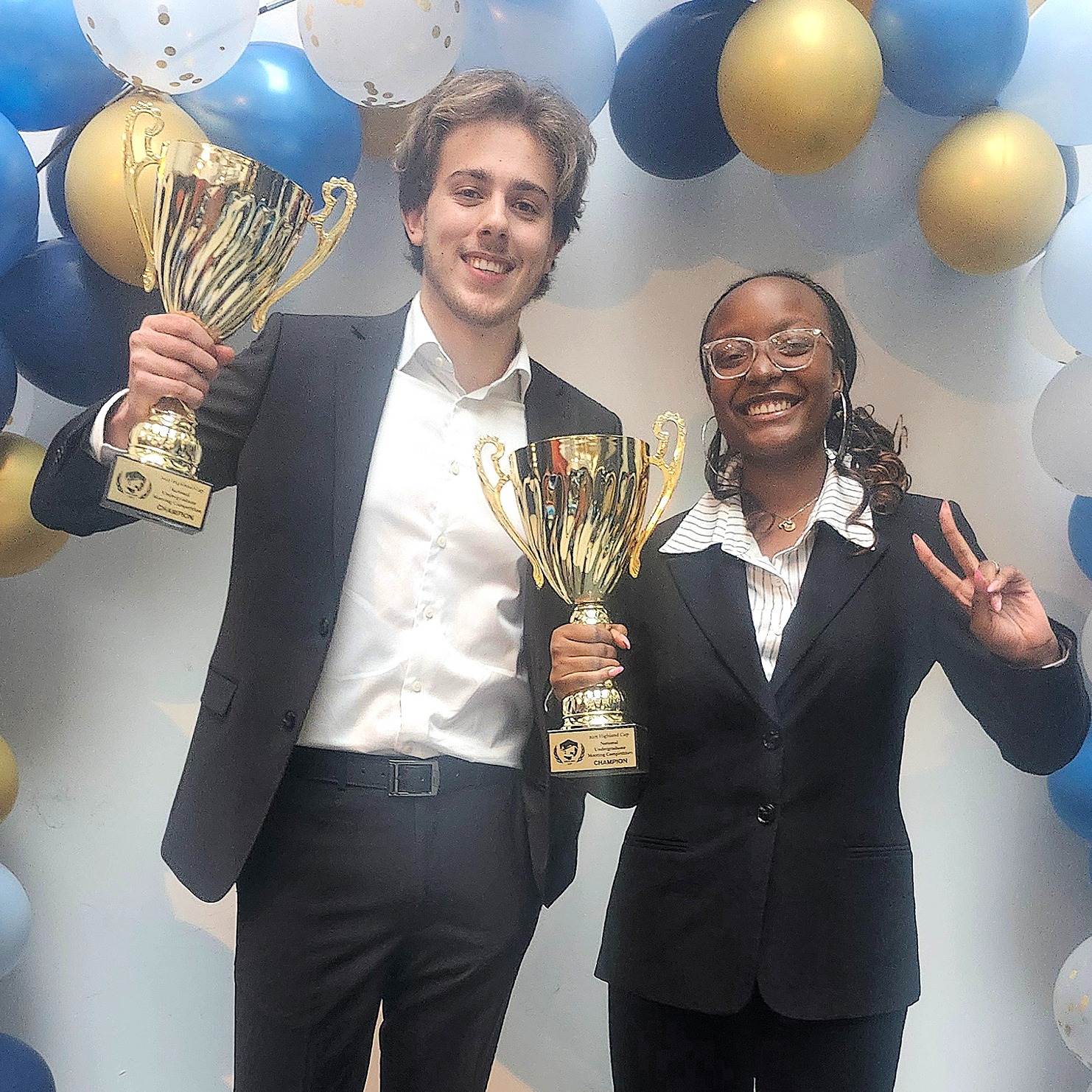 Two U of GH students hold gold trophies