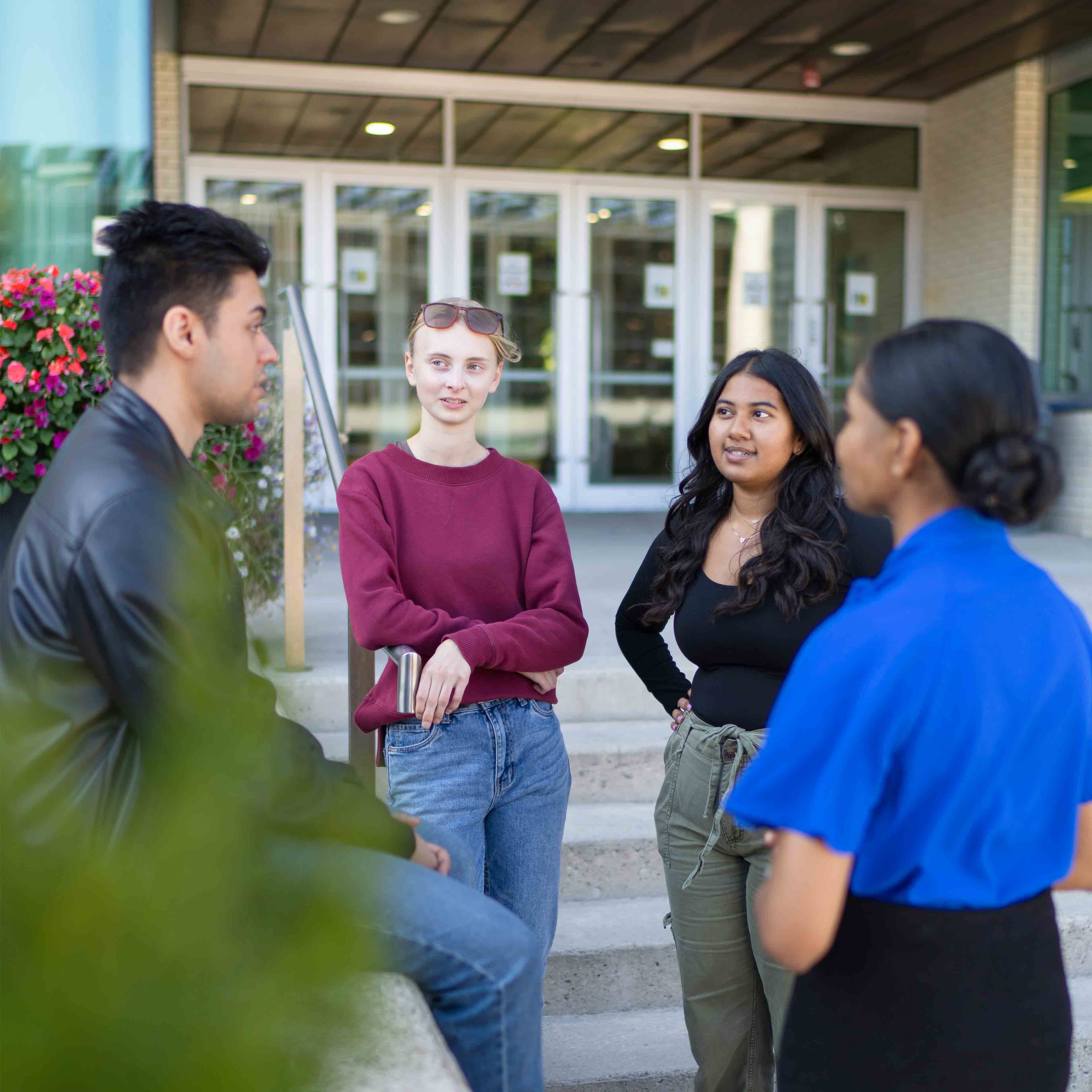 Four students stand outside of U of GH