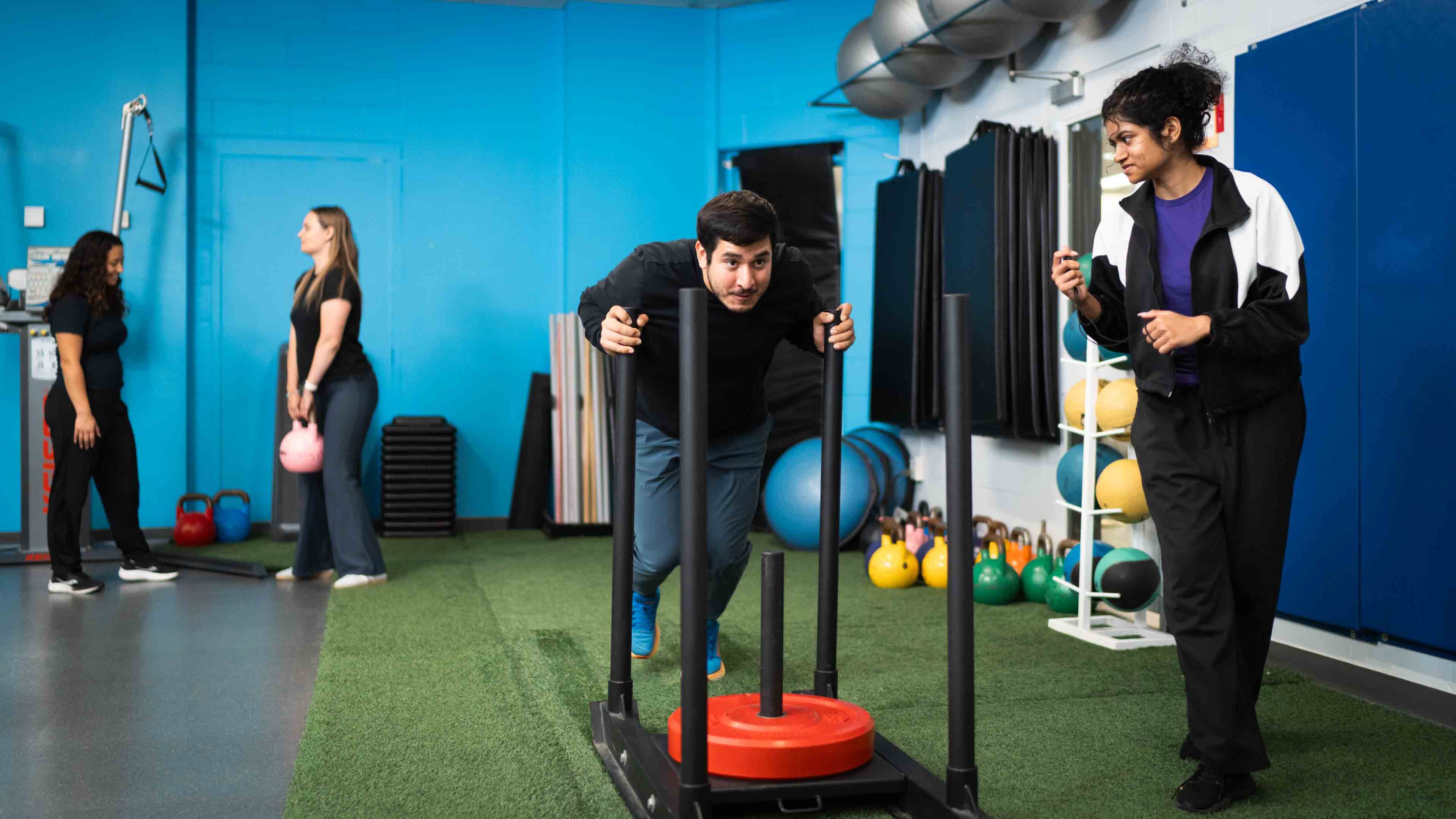 A man pushes a weighted object in a gym