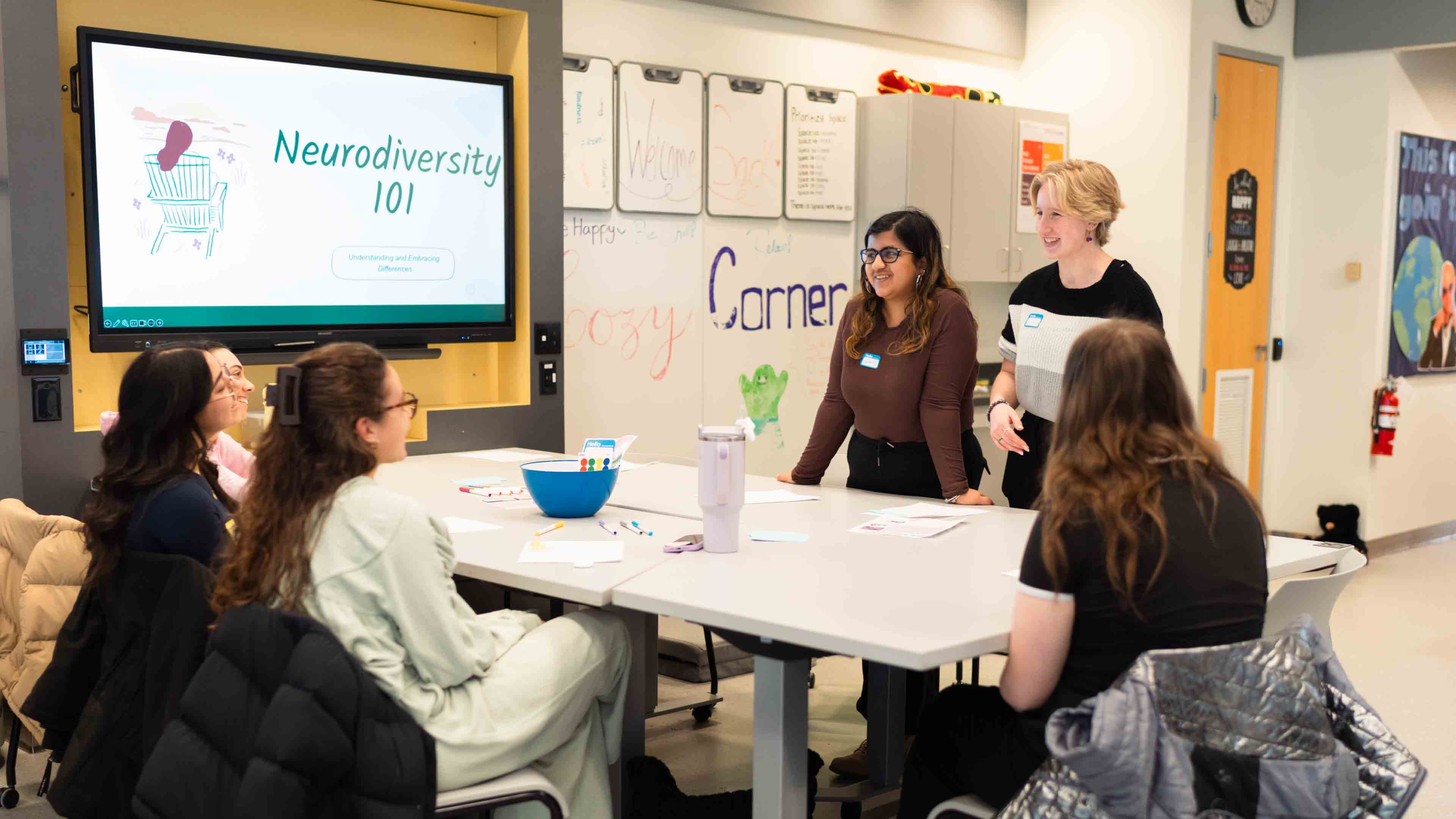 Six students gather around a table with a sign that says Neurodiversity 101