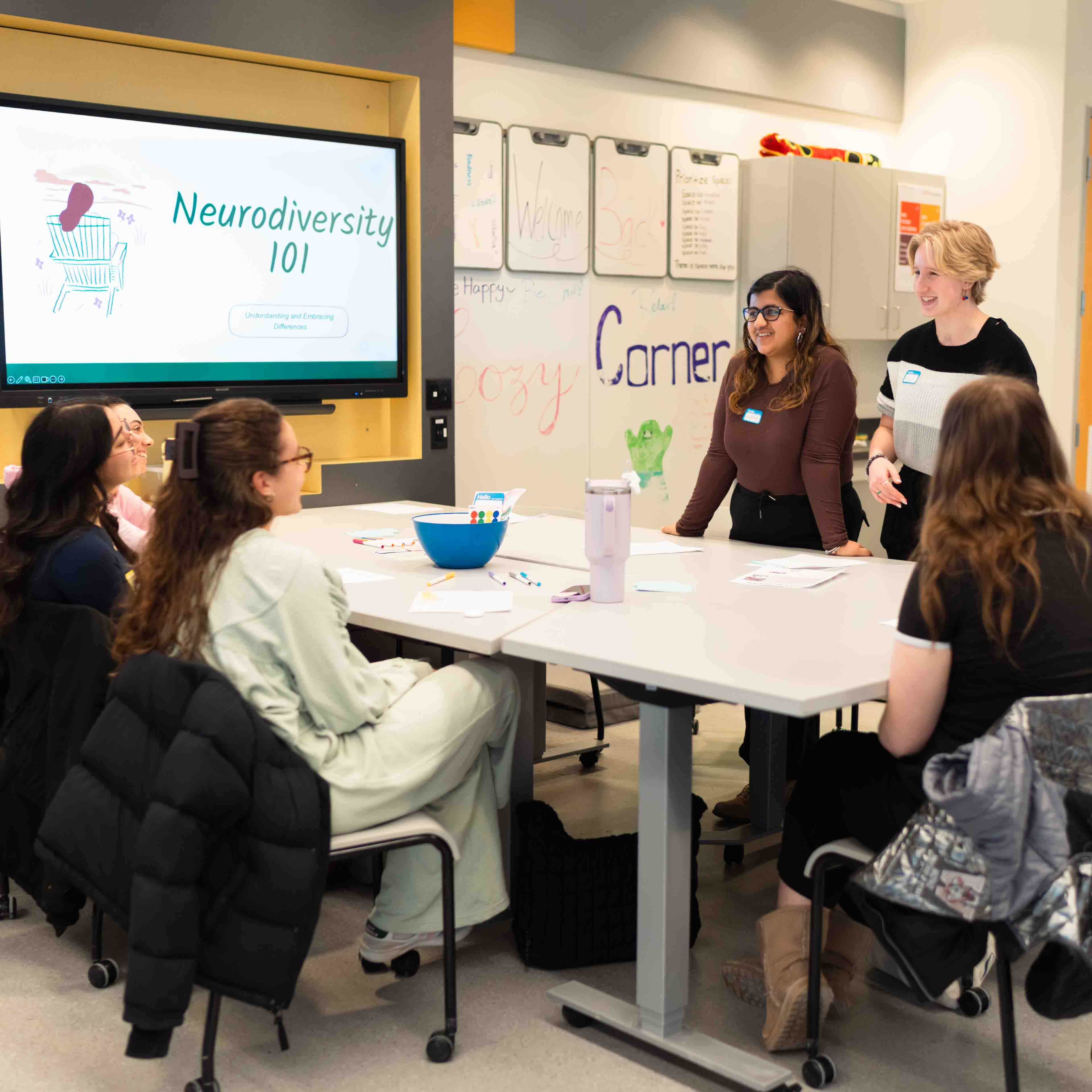 Six students gather around a table with a sign that says Neurodiversity 101
