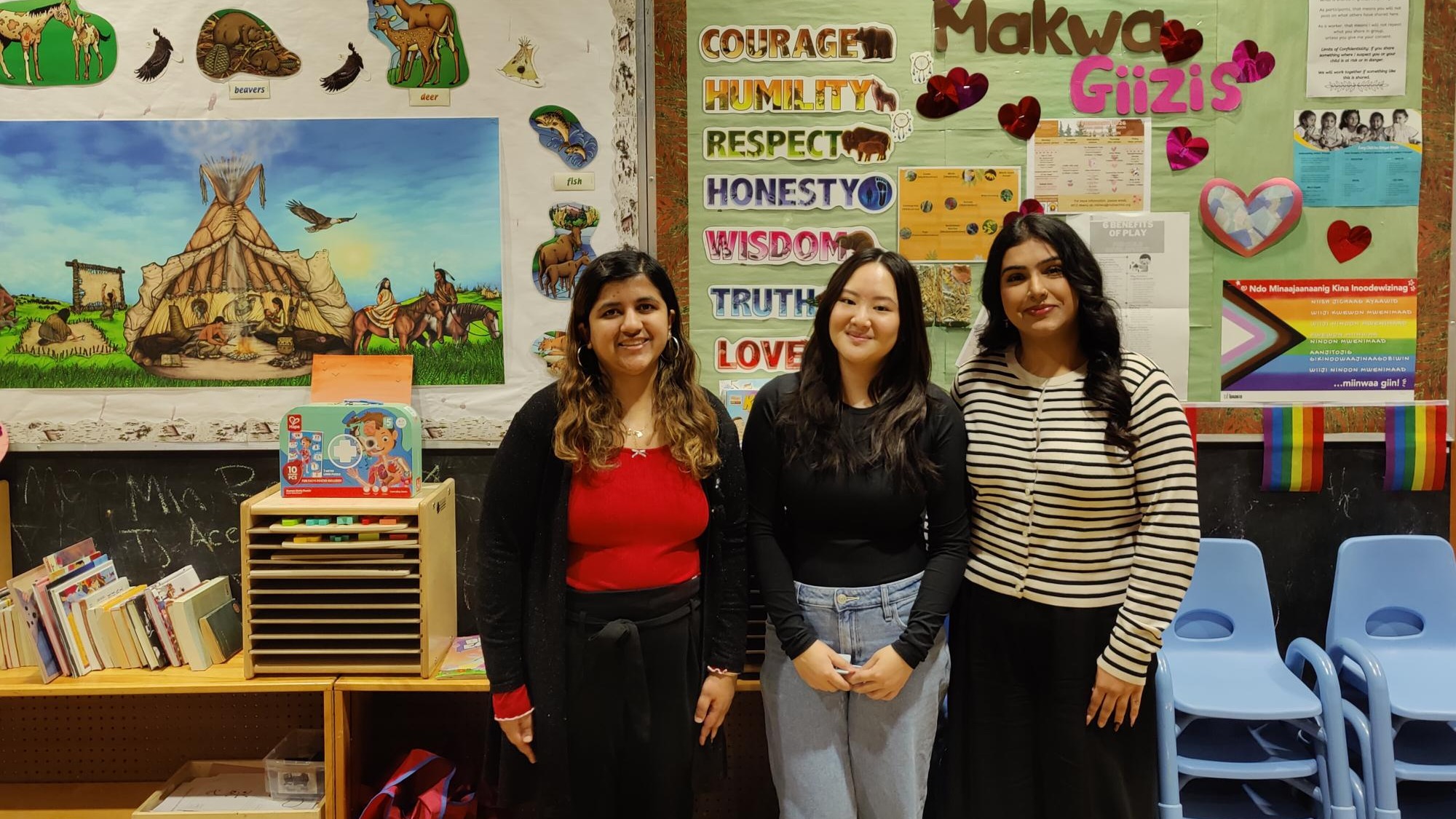 Three Guelph-Humber students stand in front of bulletin boards during the Bear Moon-themed Community Storytime event