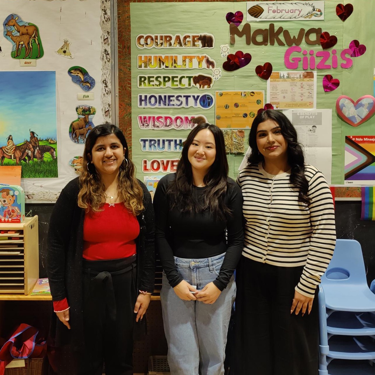 Three Guelph-Humber students stand in front of bulletin boards during the Bear Moon-themed Community Storytime event