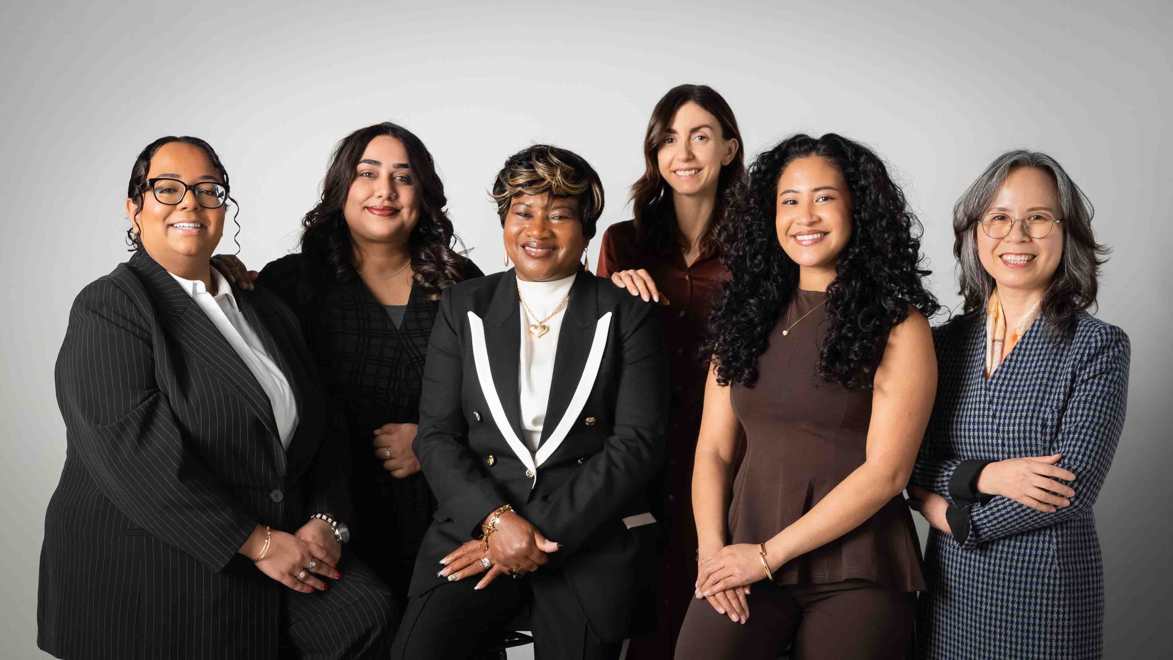 Six Women of Distinction recipients pose in front of a grey background