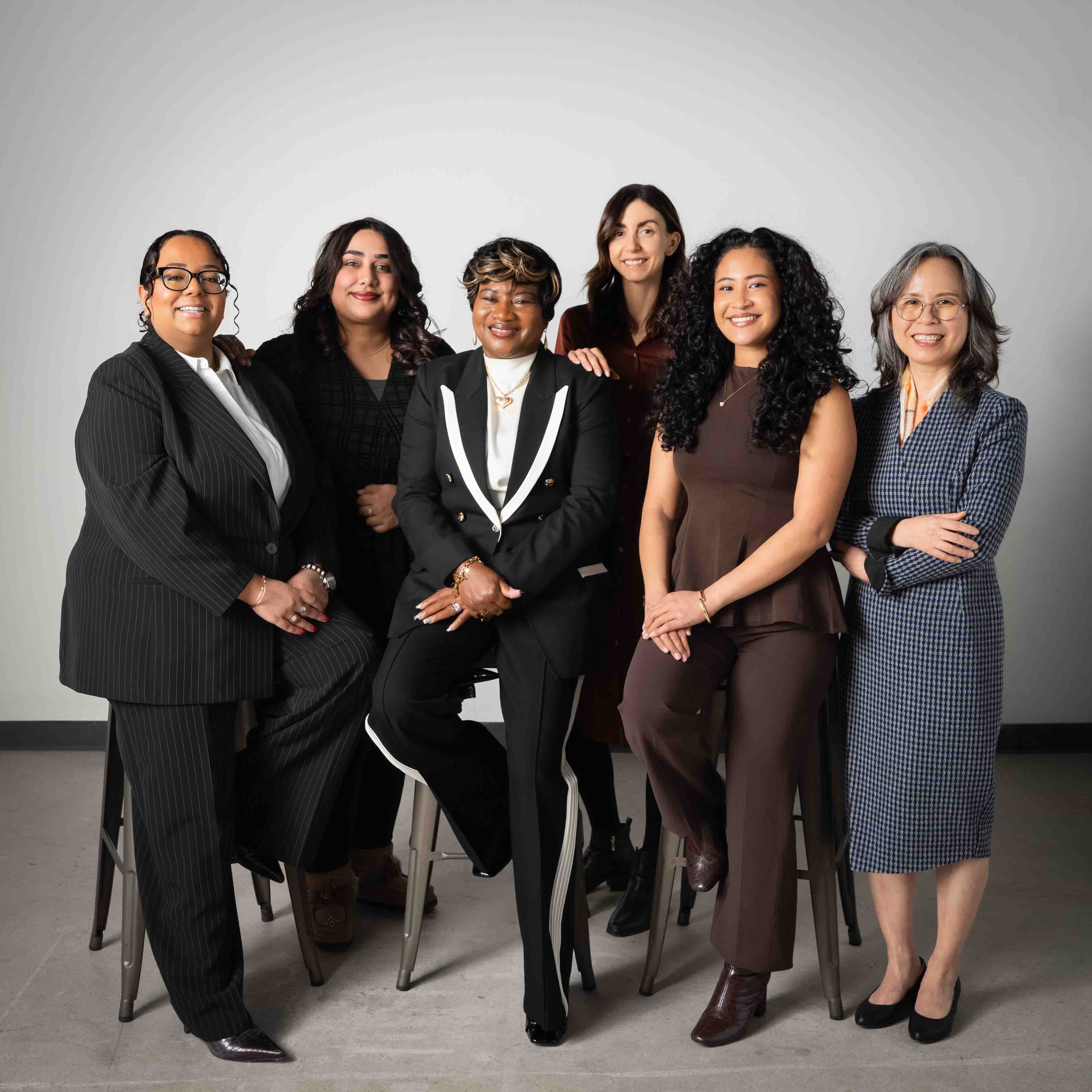 Six Women of Distinction recipients pose in front of a grey background