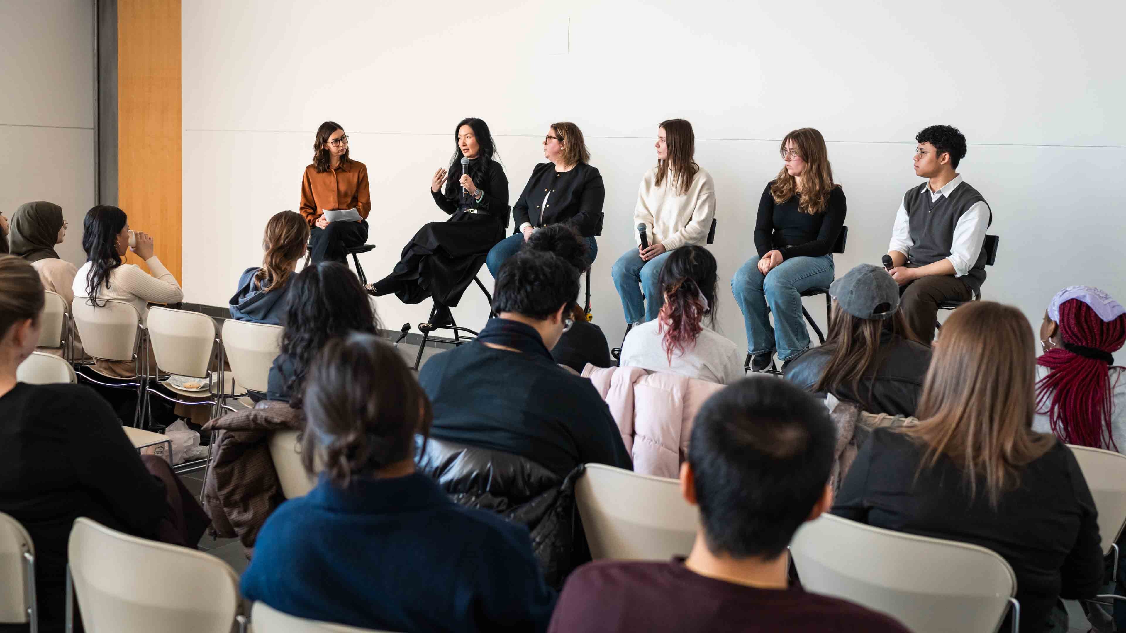 Six panellists speak in front of a packed room