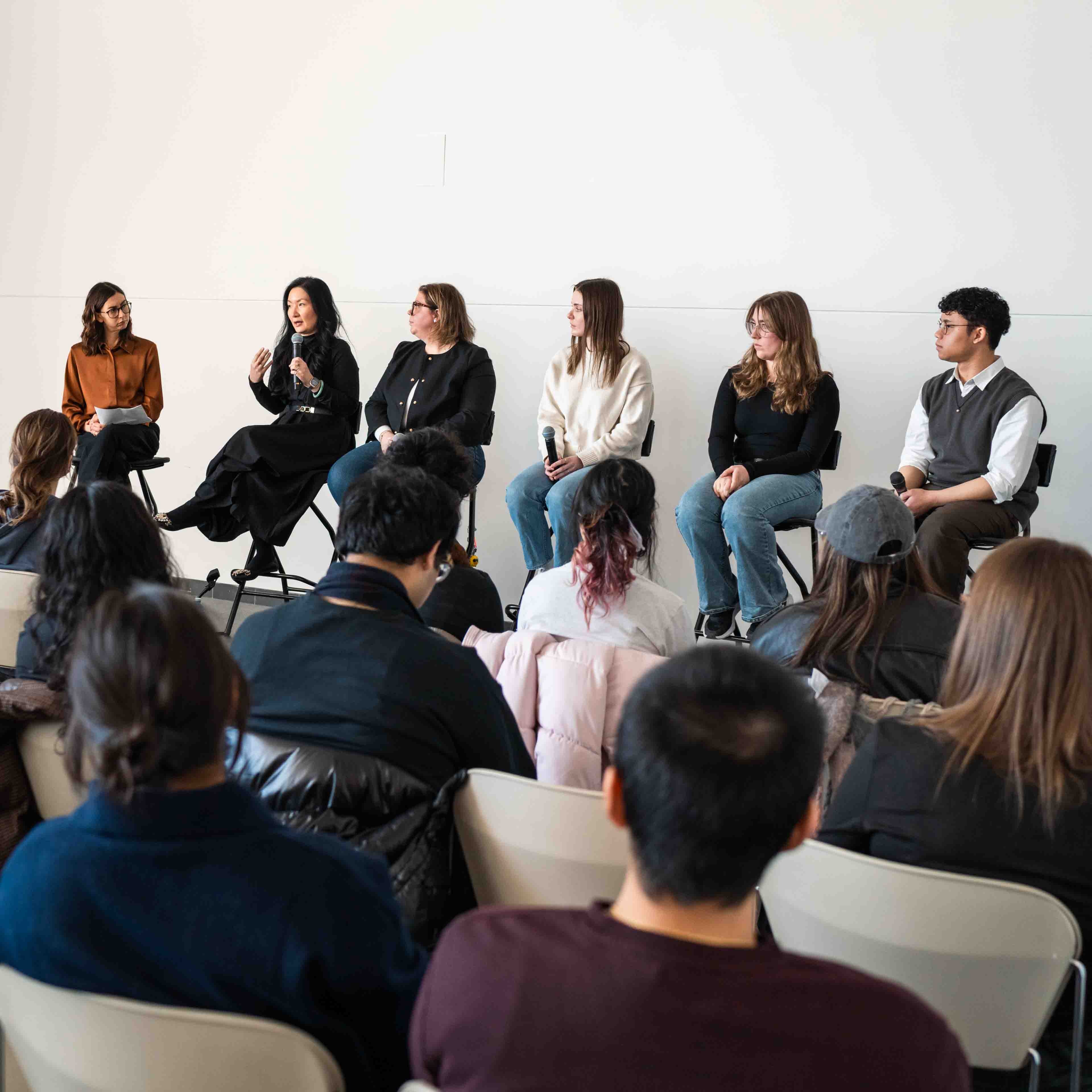 Six panellists speak in front of a packed room