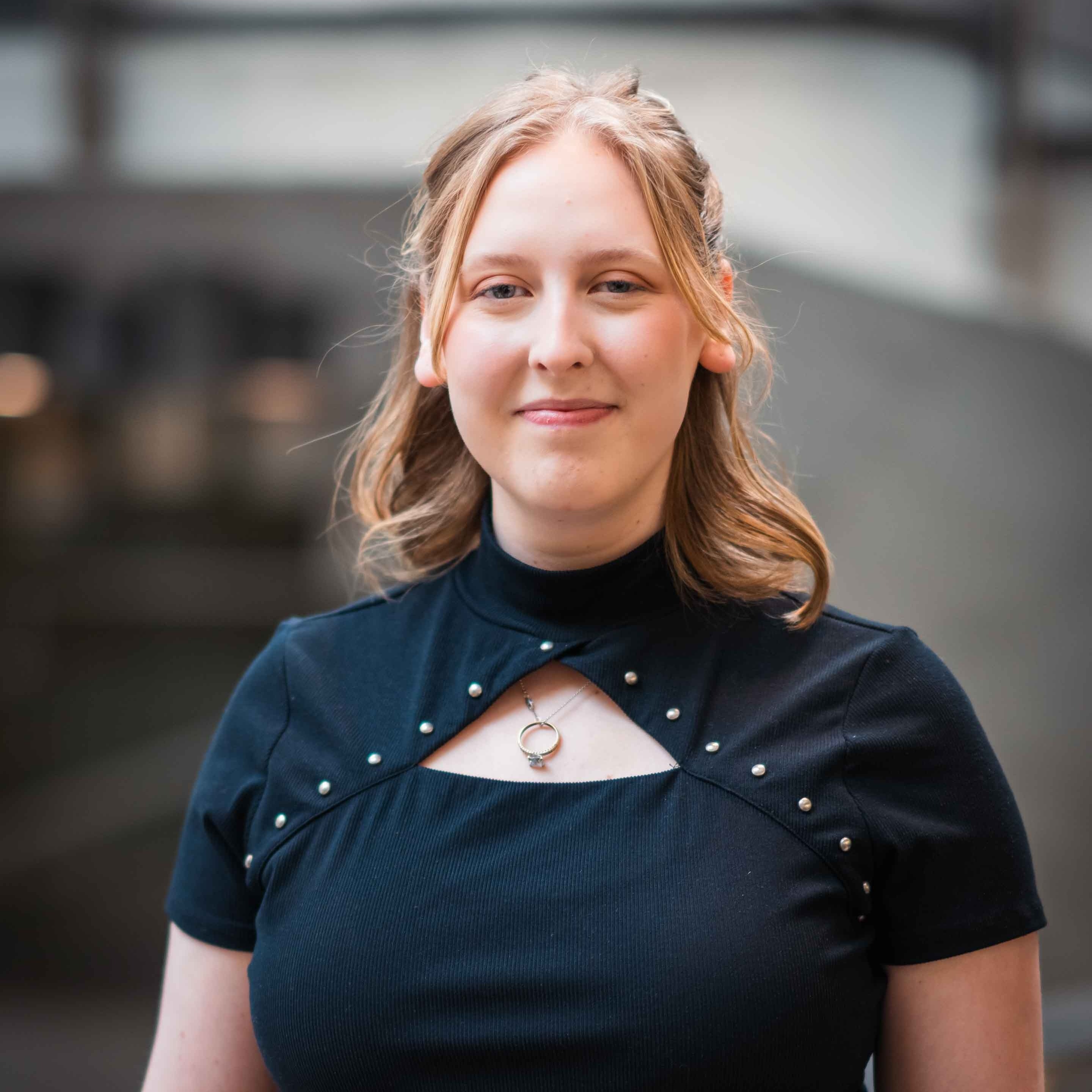 Maya Ostrom smiles by a grey background