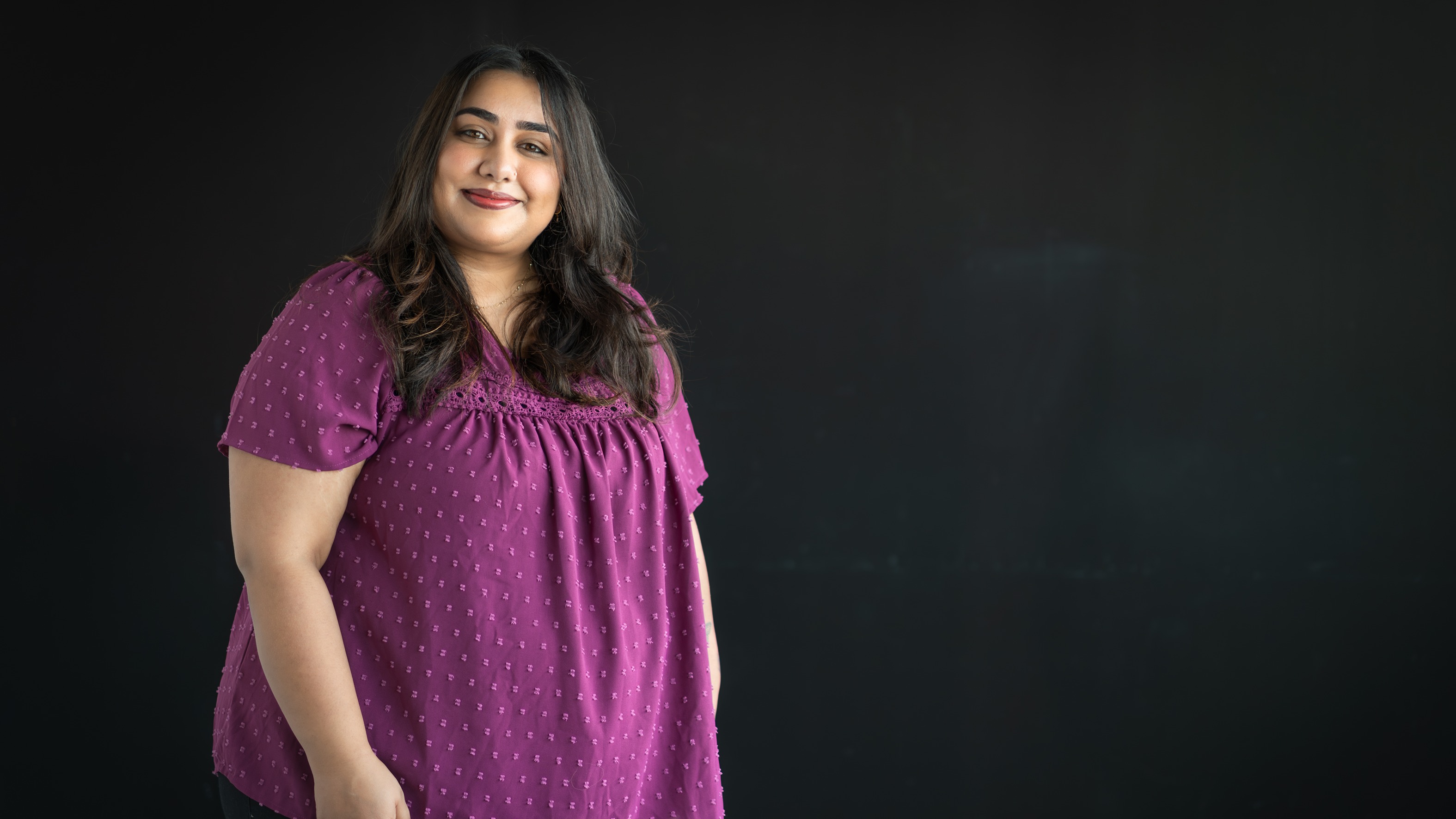 Amrit Butter smiles in front of a black backdrop