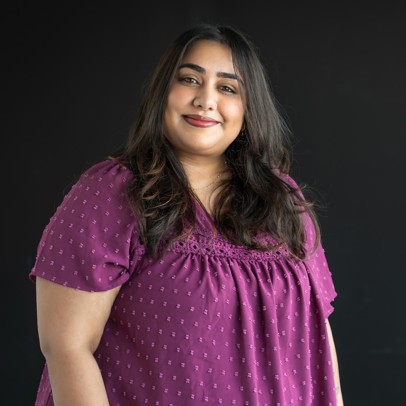 Amrit Butter smiles in front of a black backdrop