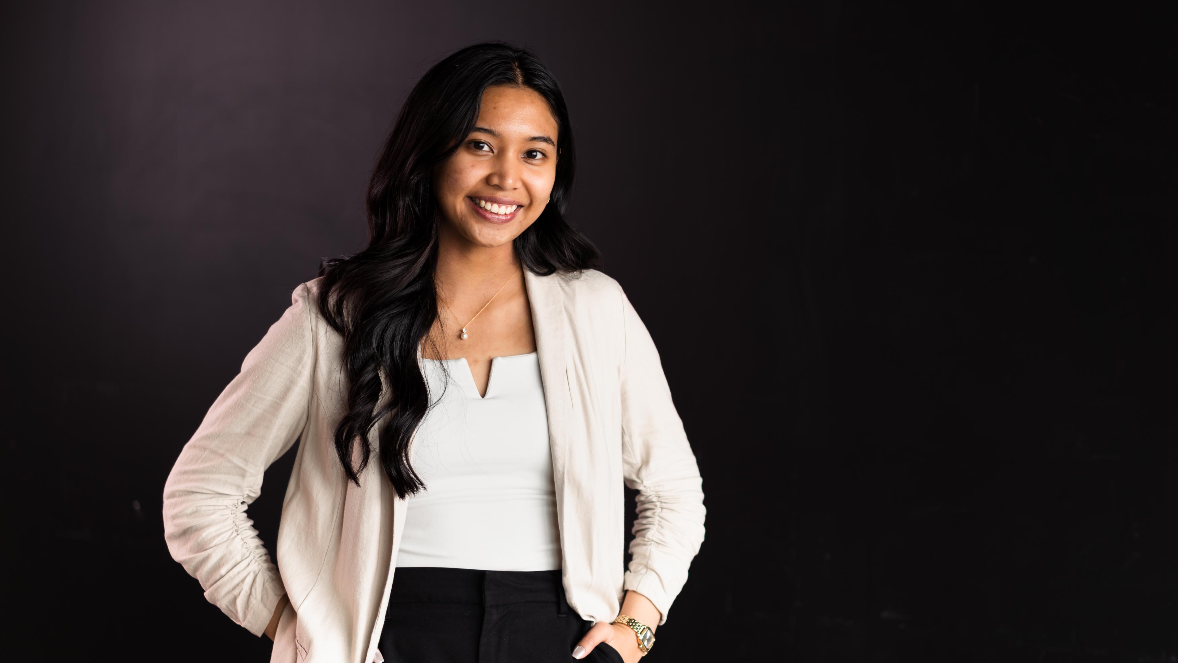 Beatrice smiles standing in front of a black backdrop