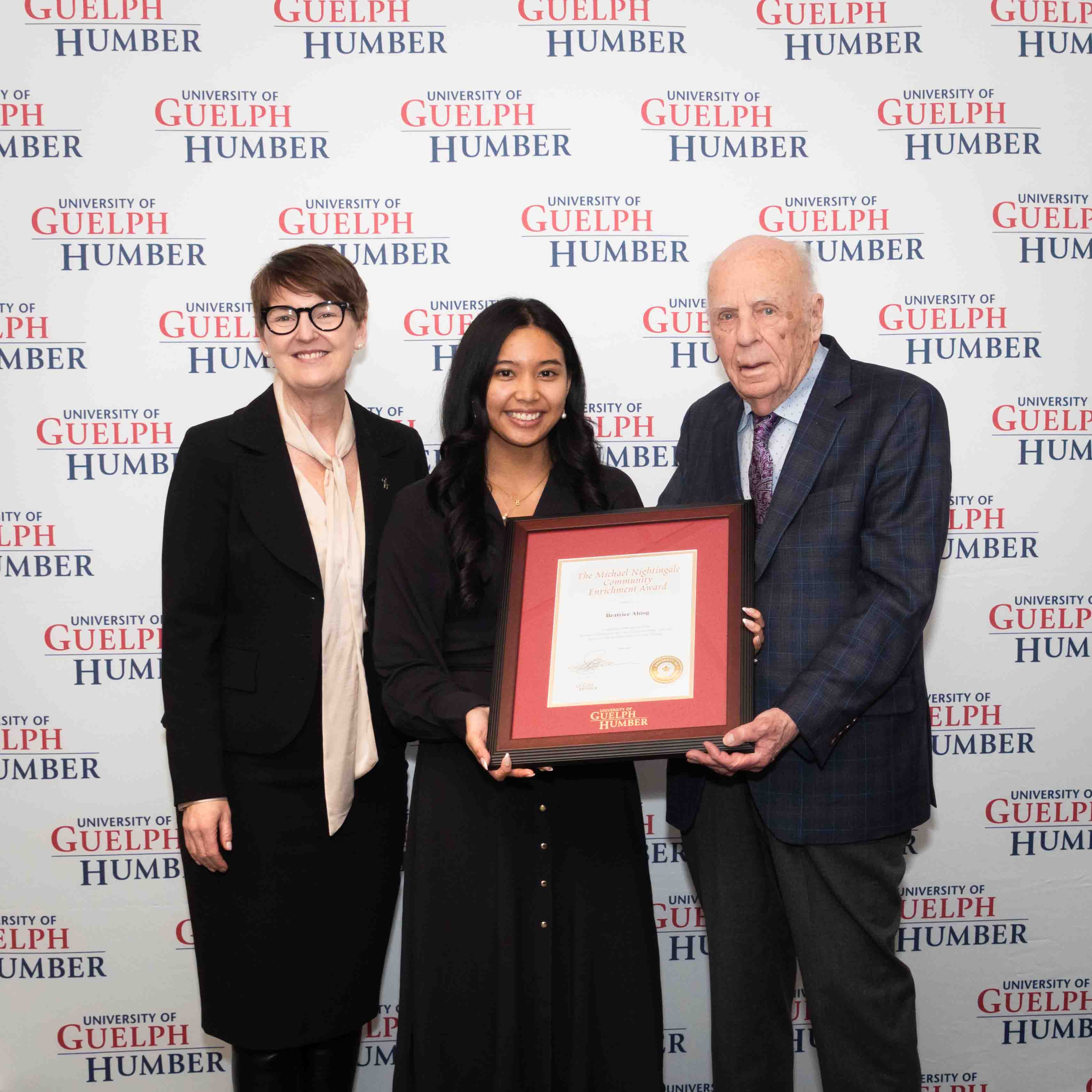 Beatrice poses with her framed award with Dr. Melanie Spence-Ariemma and Dr. Michael Nightingale