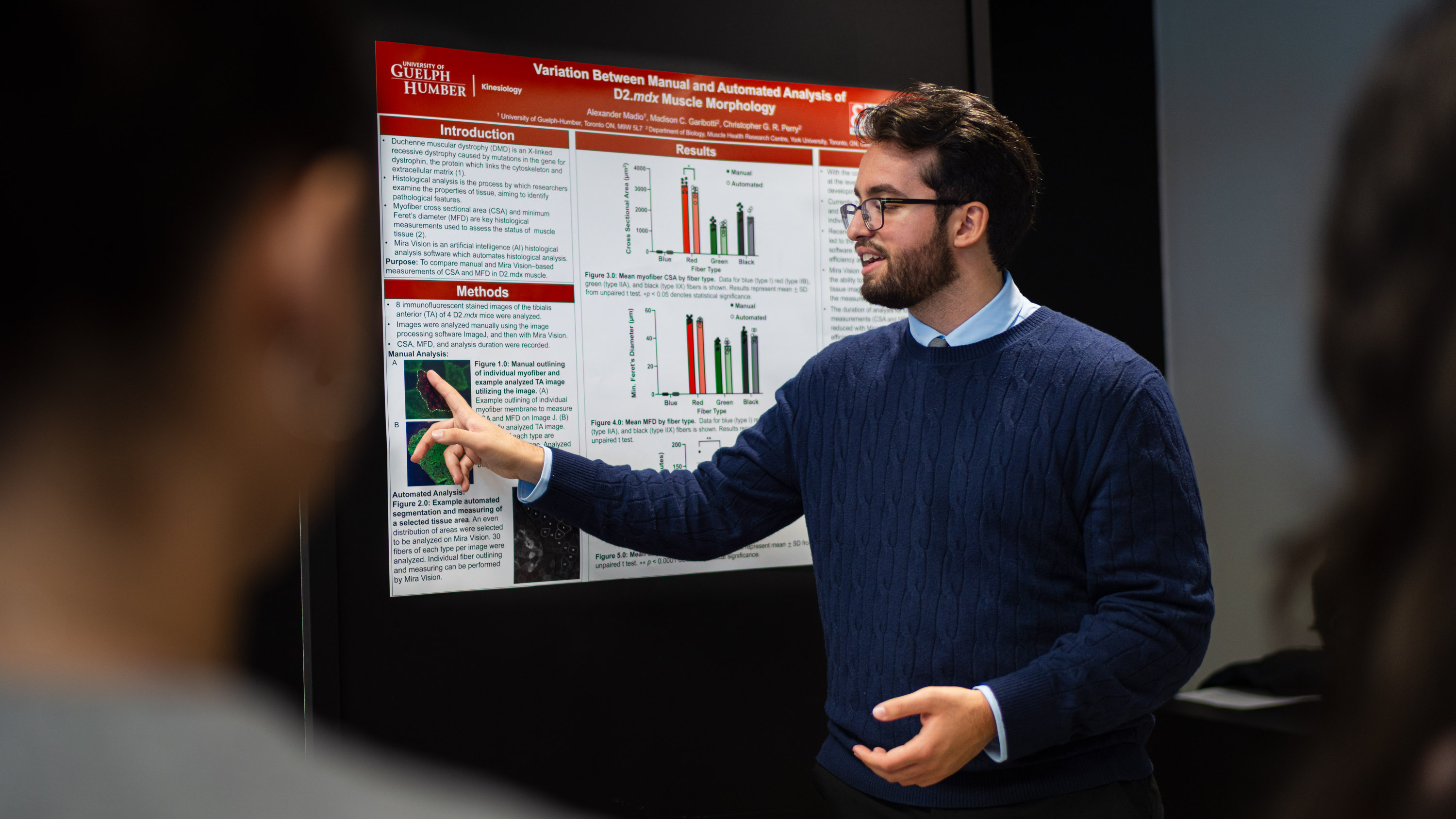 A person wearing a blue sweater points at a research poster board