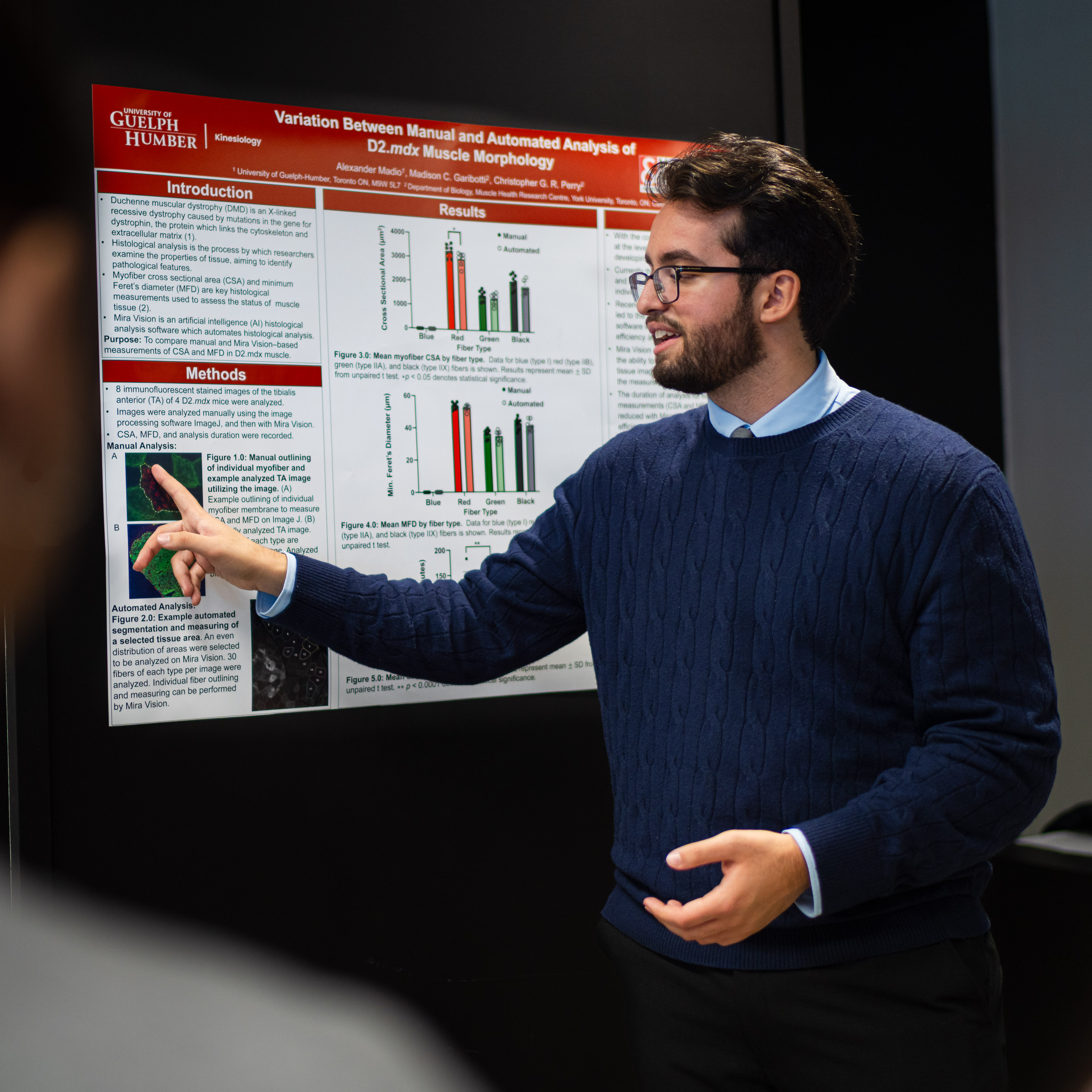A person wearing a blue sweater points at a research poster board