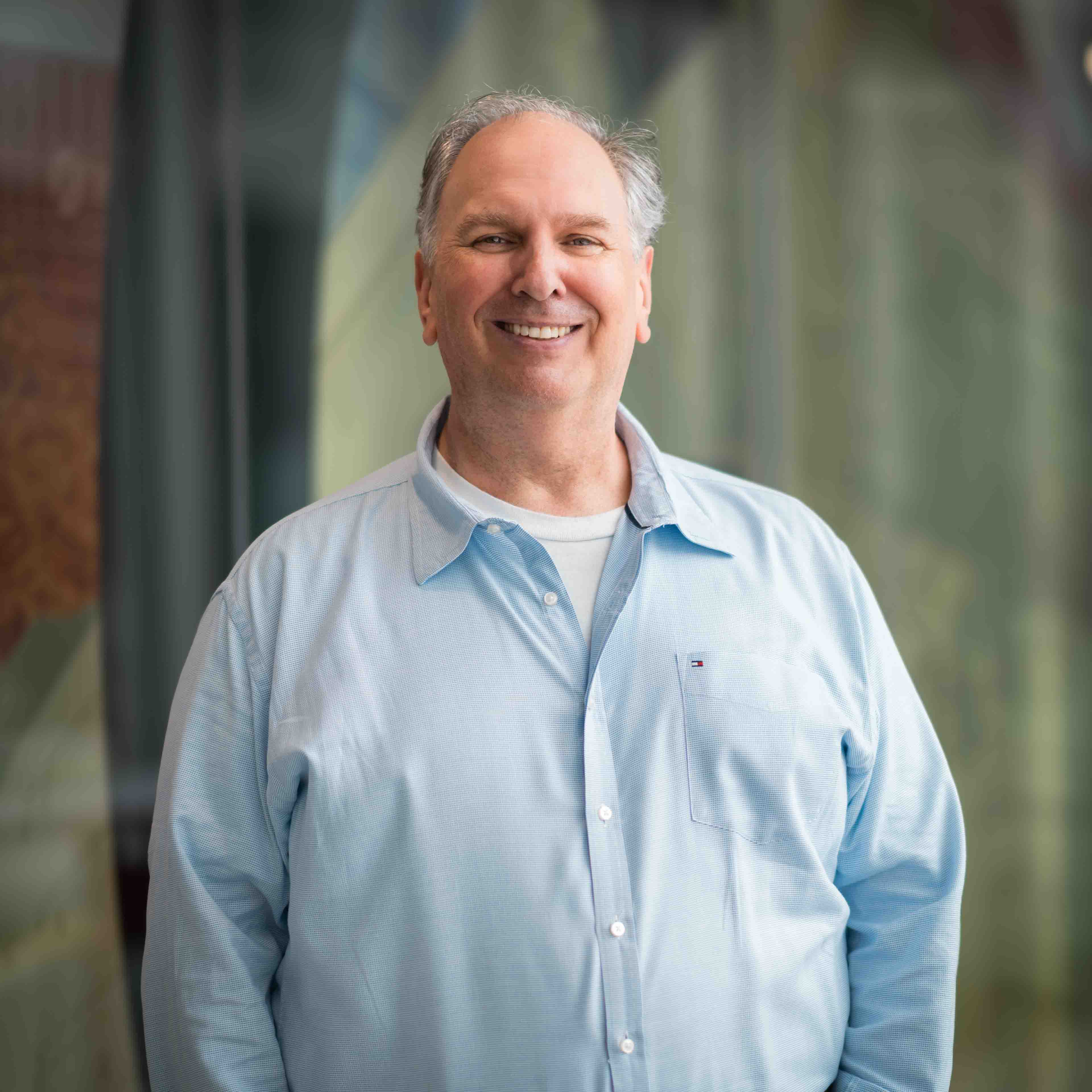 Charlie Janthur wears a blue dress shirt and smiles