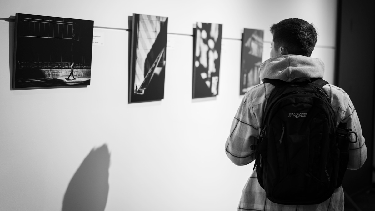 black and white photo of student looking at art on the wall