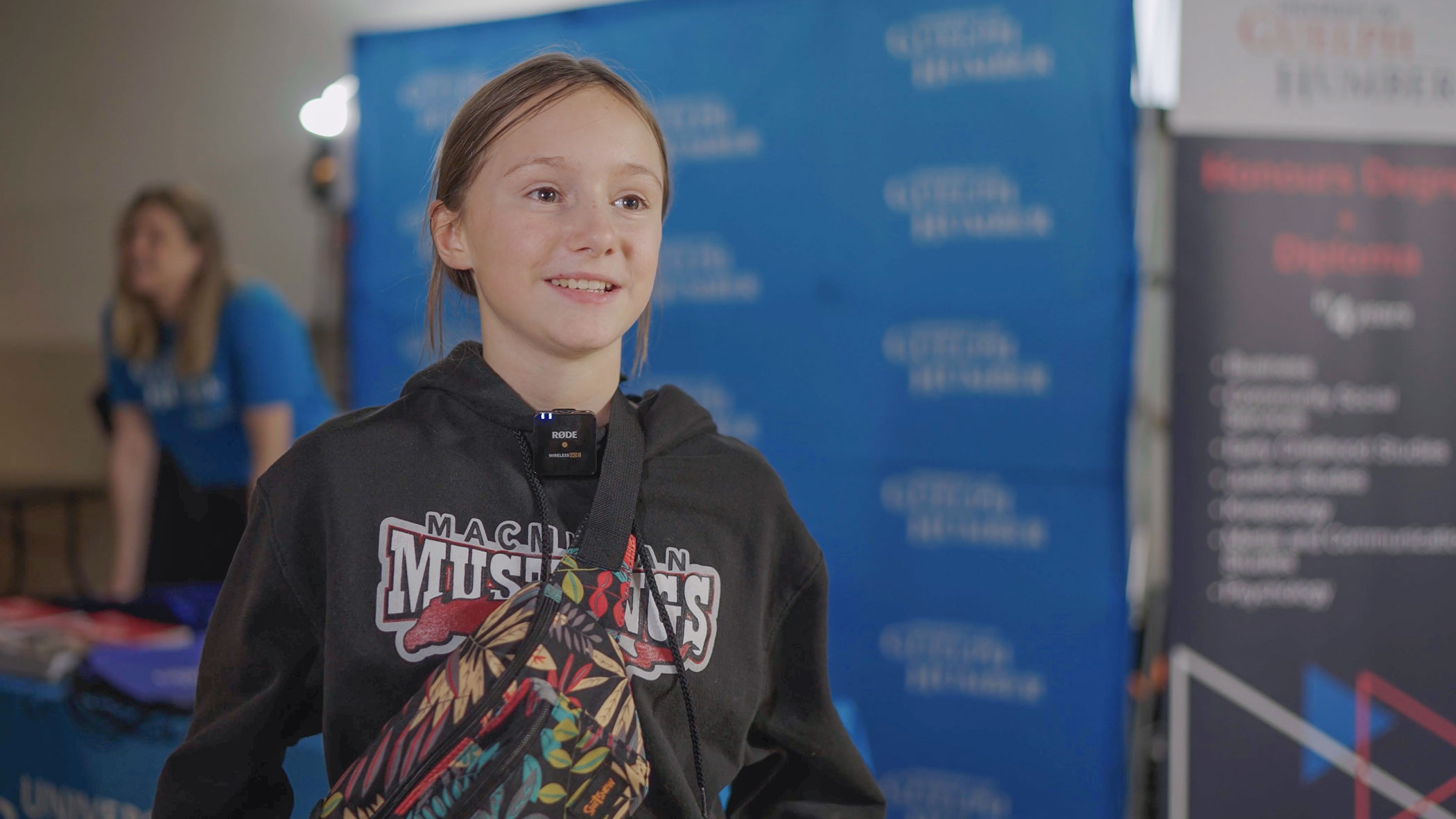 Someone looking off-camera being interviewed in front of a blue University of Guelph-Humber step-and-repeat