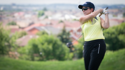 Photo of UofGH staff member swinging golf club