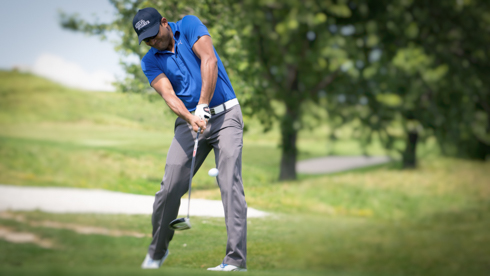 Photo of UofGH alumni striking golf ball with club