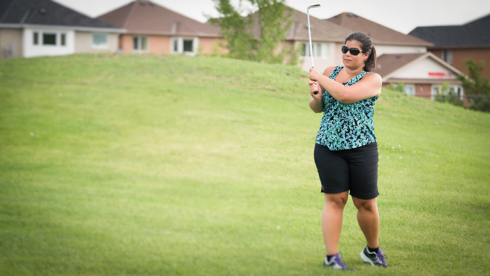 Photo of UofGH alumni swinging golf club