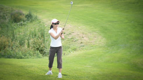 Photo of UofGH alumni swinging golf club