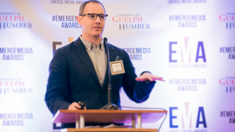 Man giving a speech at podium with a hand half raised in emphasis_