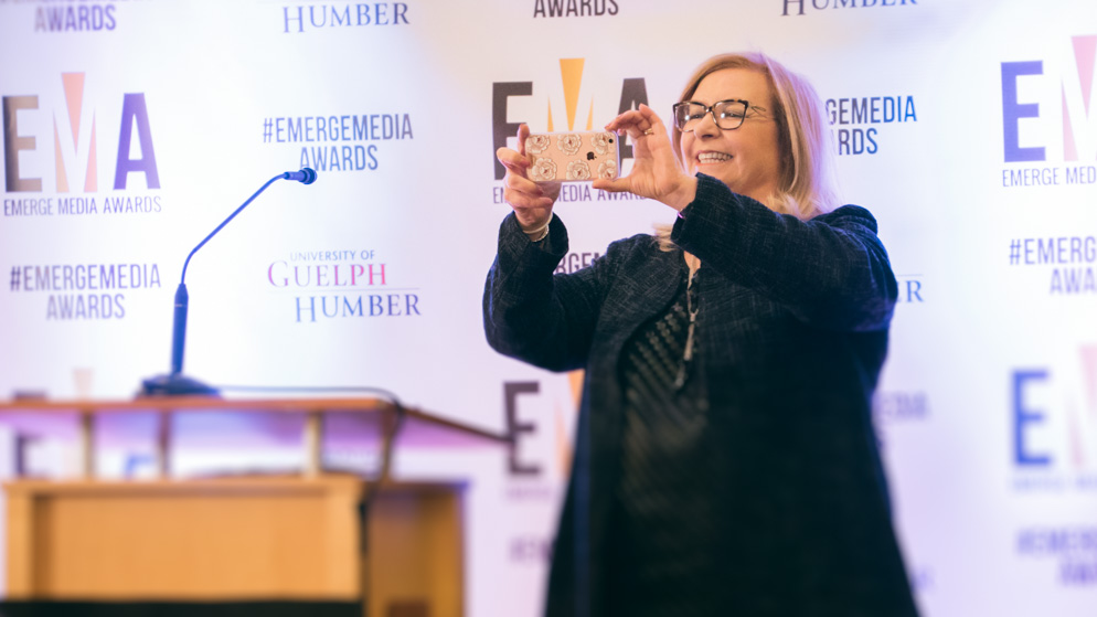 Woman on stage taking a photo of the crowd on her smartphone_