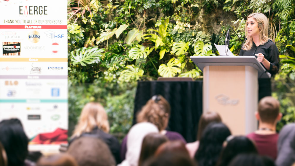 Host at podium with seated crowd in foreground_