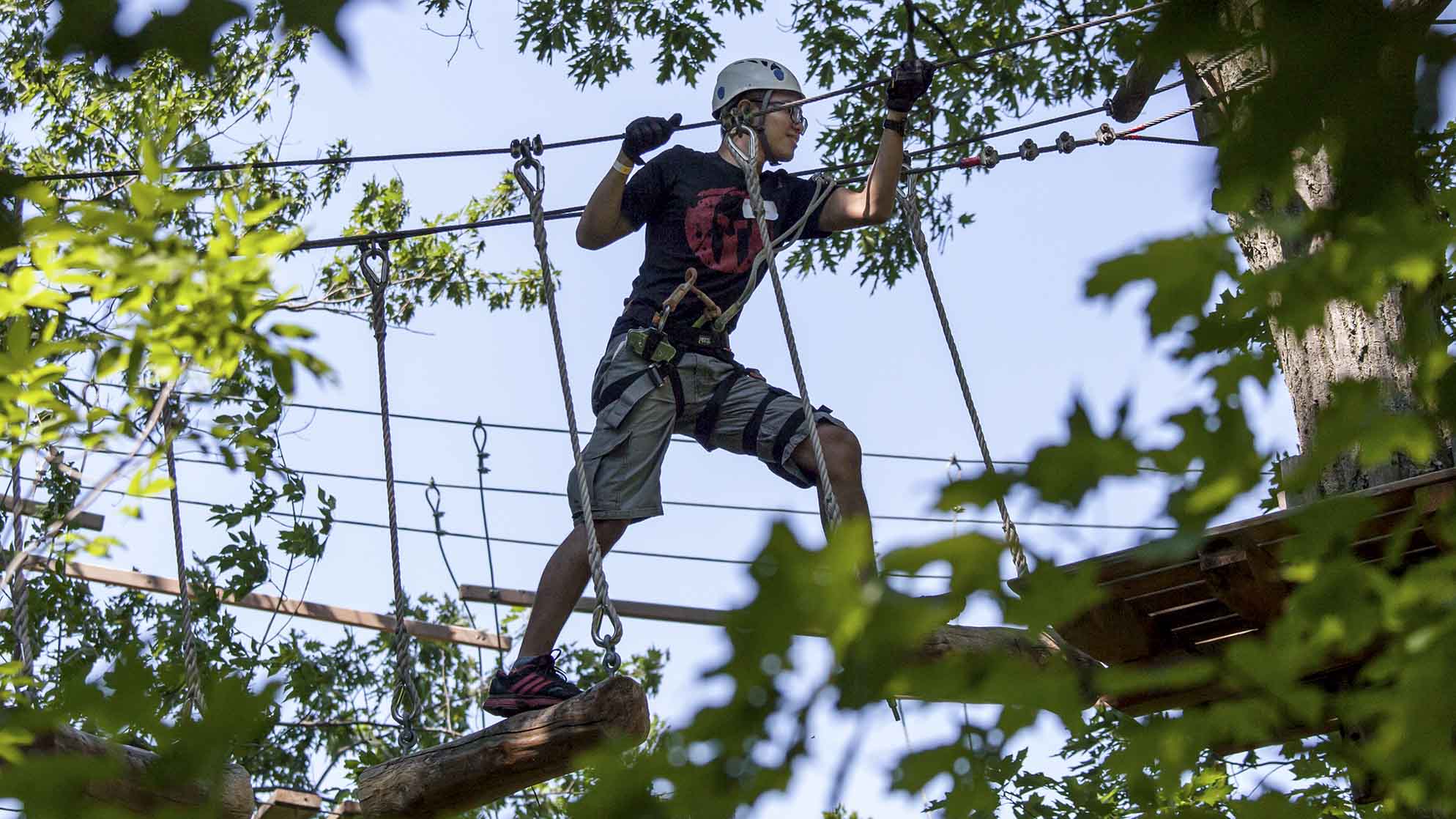 An alum walks on a bridge between trees