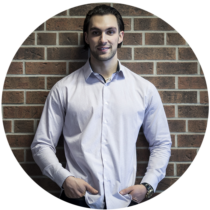 Nick Foglia smiles in front of a brick wall