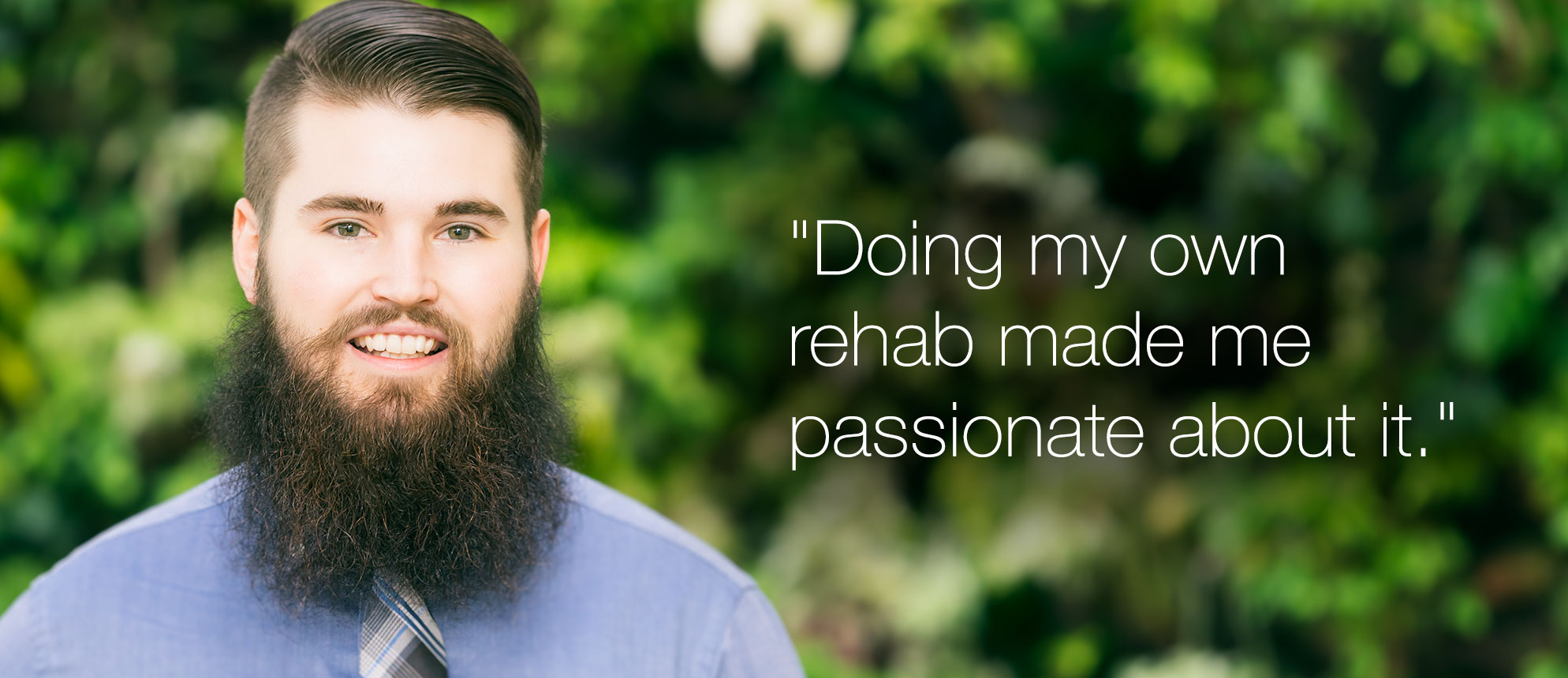 Kinesiology student Nicholas Graham poses in front of plant wall.