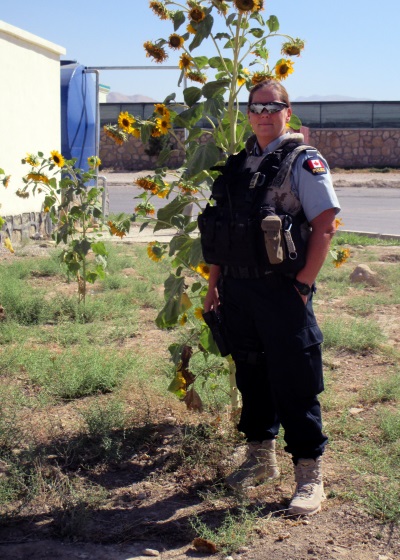 Professor O'Toole is wearing a policing uniform and is standing infront of tall sunflowers.