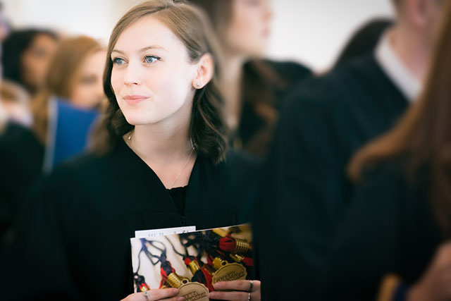 A graduate waits her turn to enter the auditorium