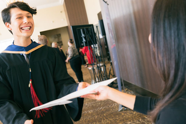 A graduate grins as he shakes hands