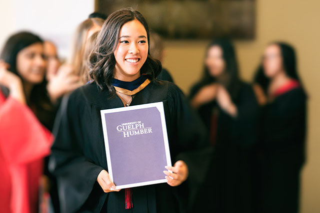 A graduate smiles as she waits to receive her degree